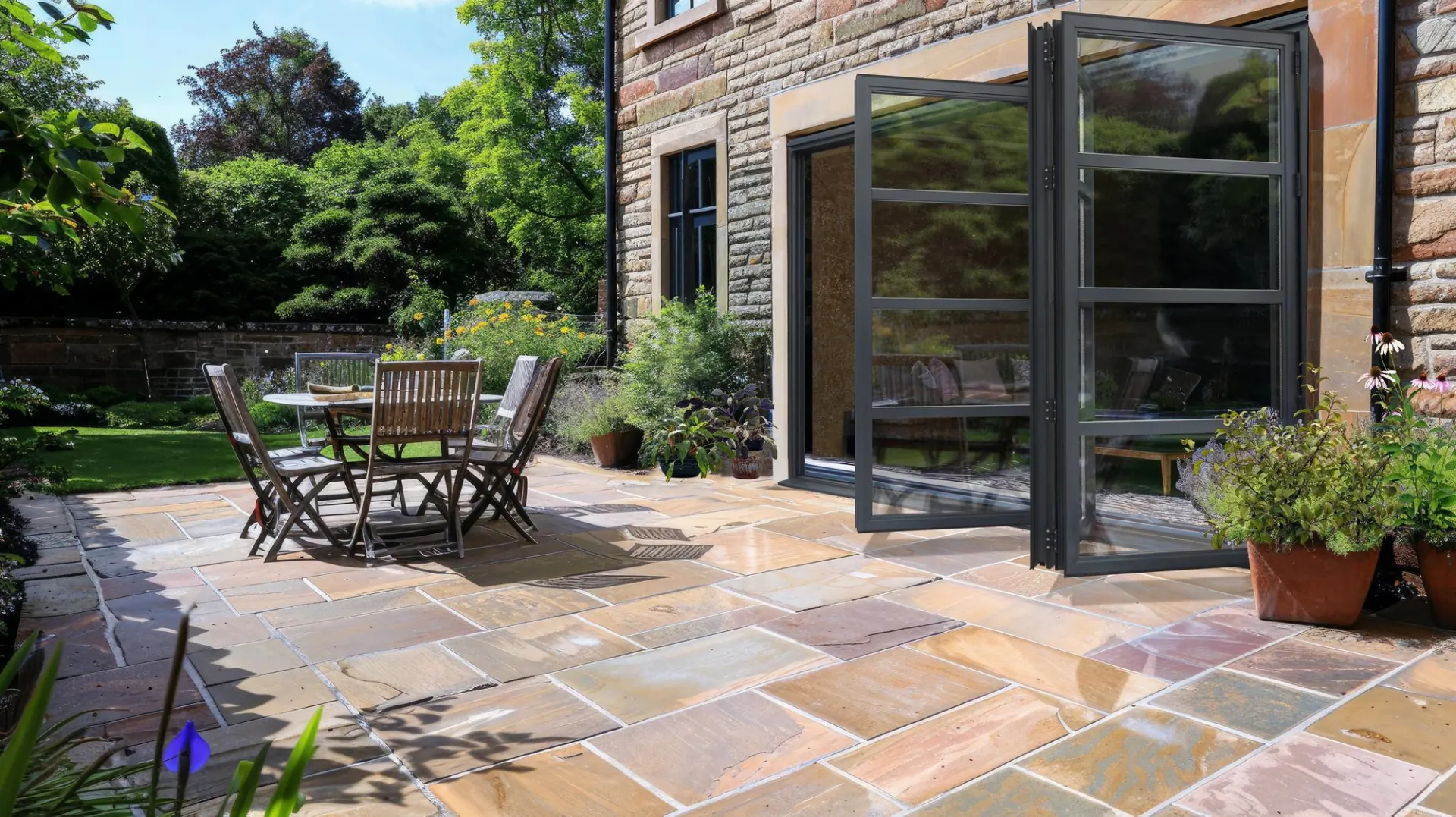 APX Fold aluminium bifold doors in grey opening onto a stone terrace